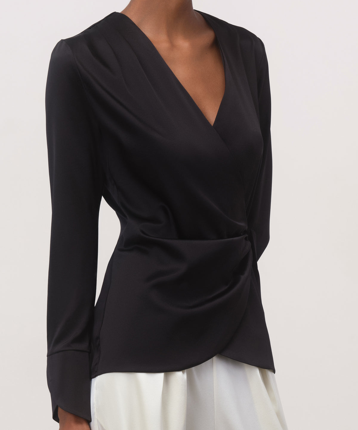 Close-up of black 19 momme mulberry silk charmeuse wrap blouse with surplice V-neckline and waist gathering