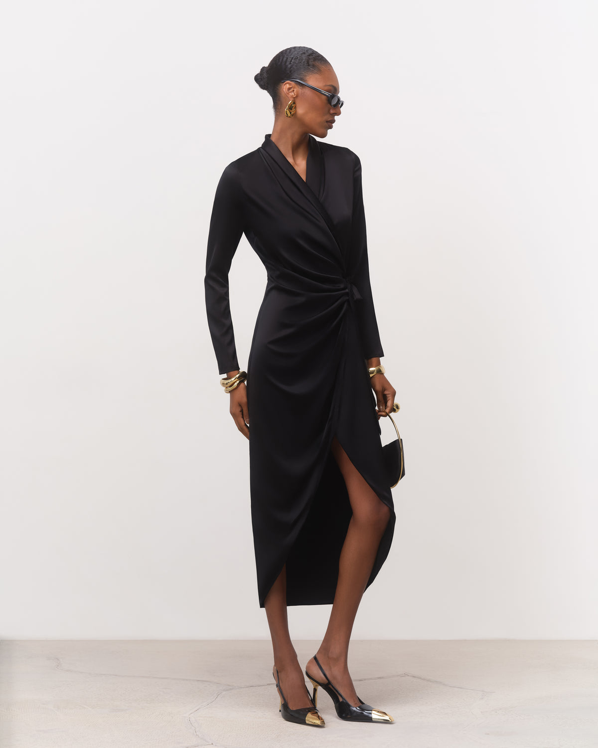 Women's black silk midi dress with asymmetrical front-slit hem, three-quarter view
