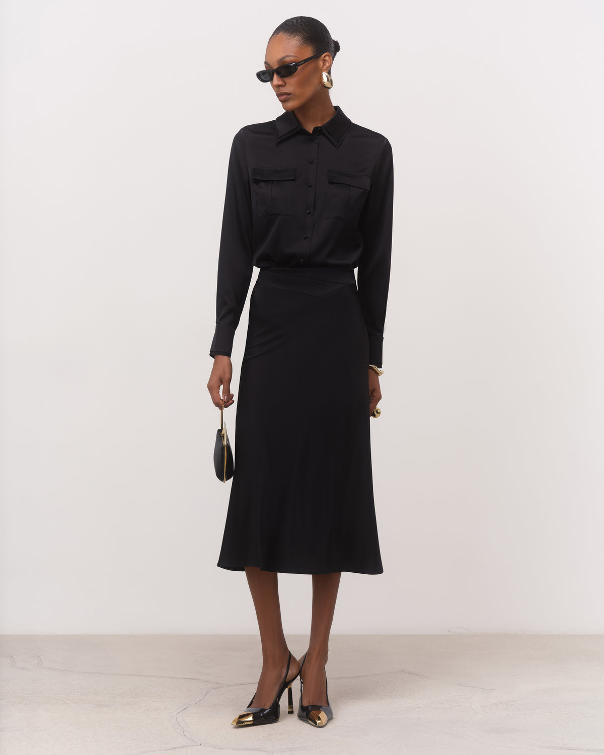 Anitas Muse Dubai black bias cut silk midi skirt for women, worn with a black silk shirt, front view