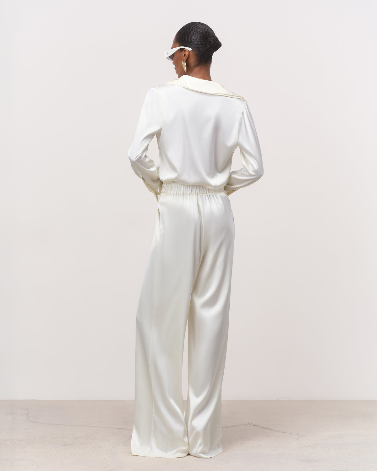 Back view of pearl off-white silk belted shirt and wide-leg trousers with flared peplum hem