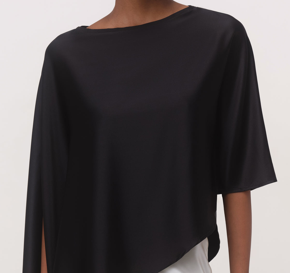 Close-up of black mulberry silk cape top with boat neckline, cape sleeve and asymmetric hem