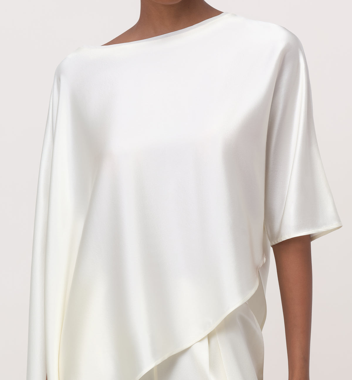 Close-up of white mulberry silk cape top with boat neckline, cape sleeve and asymmetric drape