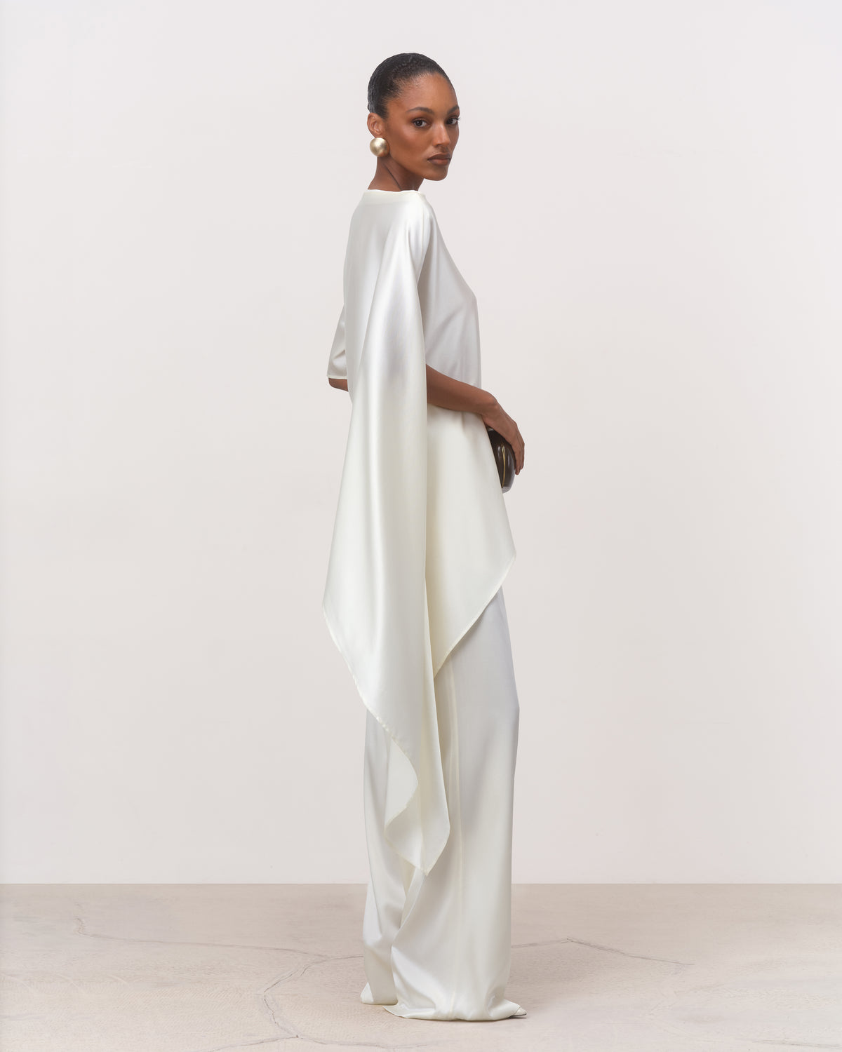 Side view of pearl off-white silk cape top with floor-grazing asymmetric drapesss