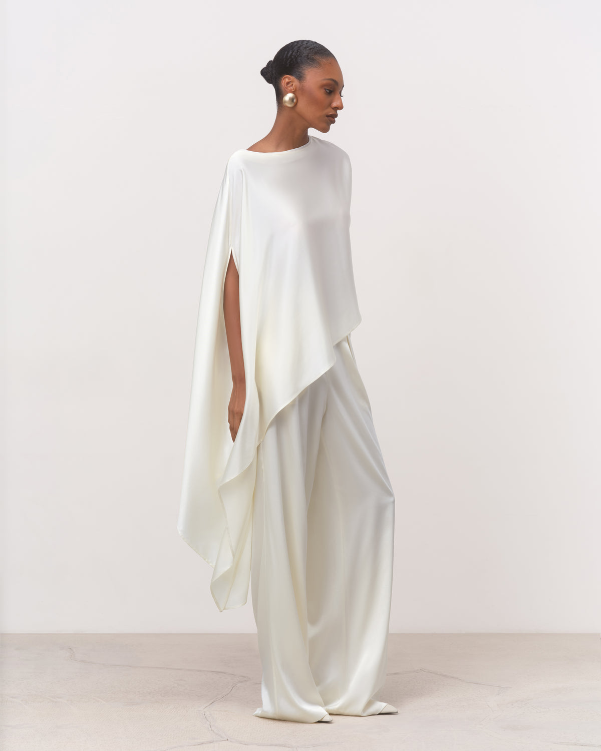 Women's white draped silk top with flowing cape hem, three-quarter view